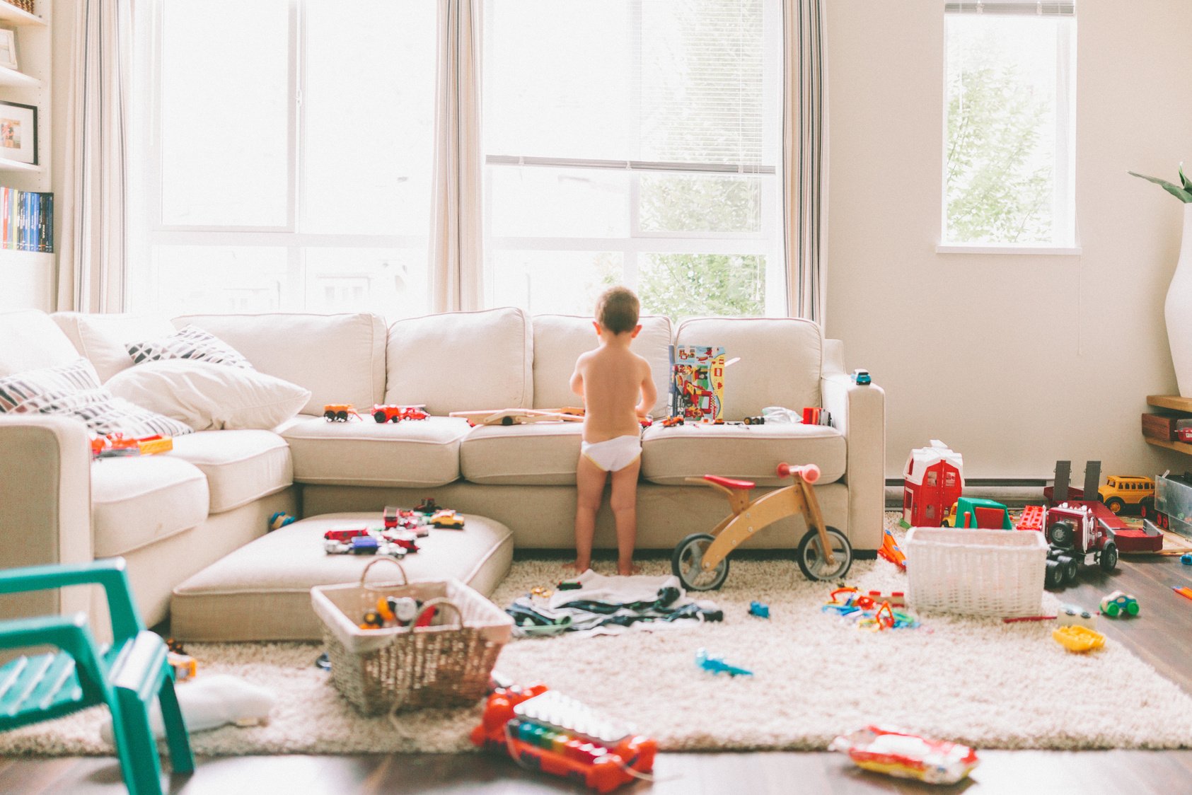 Messy house with toddler playing toys in the living room